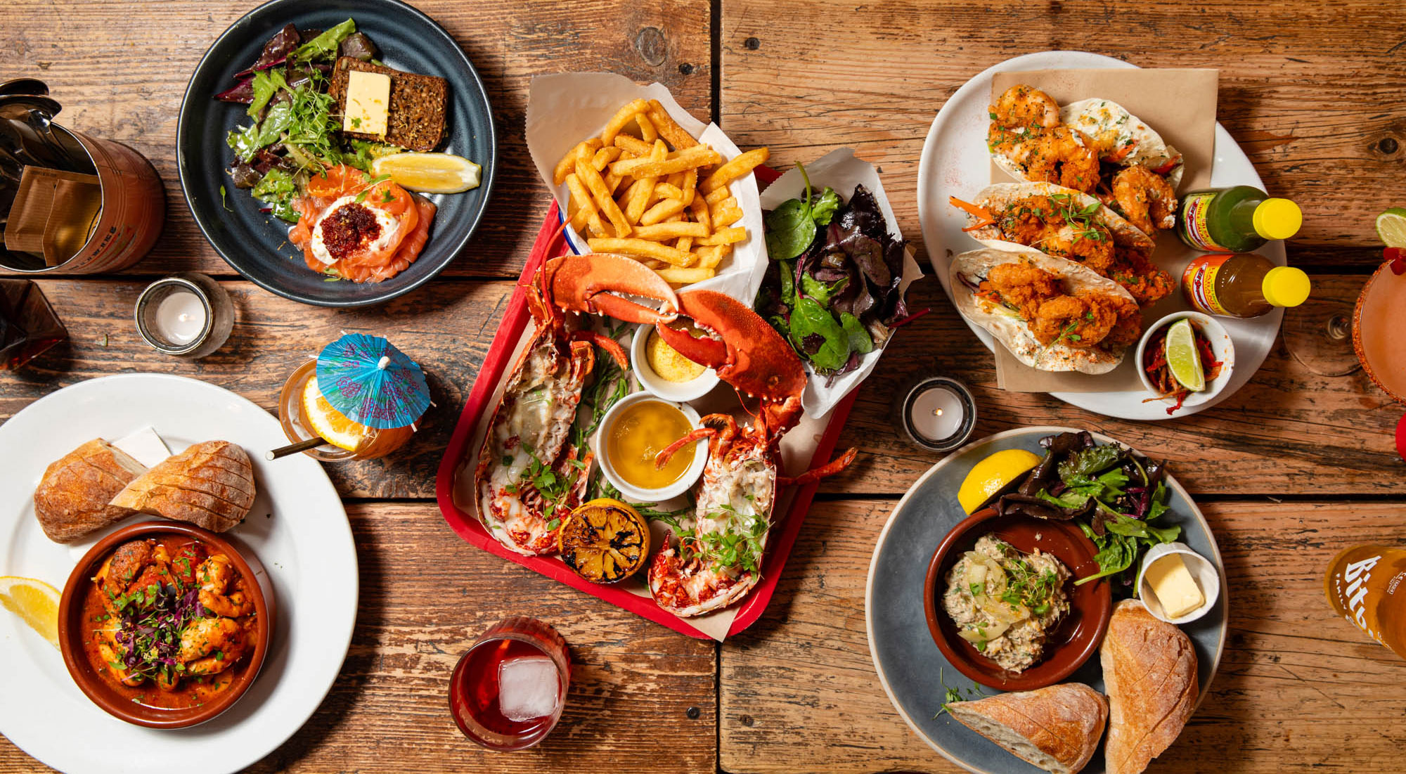 An overhead spread of Crabshack seafood, lobster, prawns and sides on rustic wood