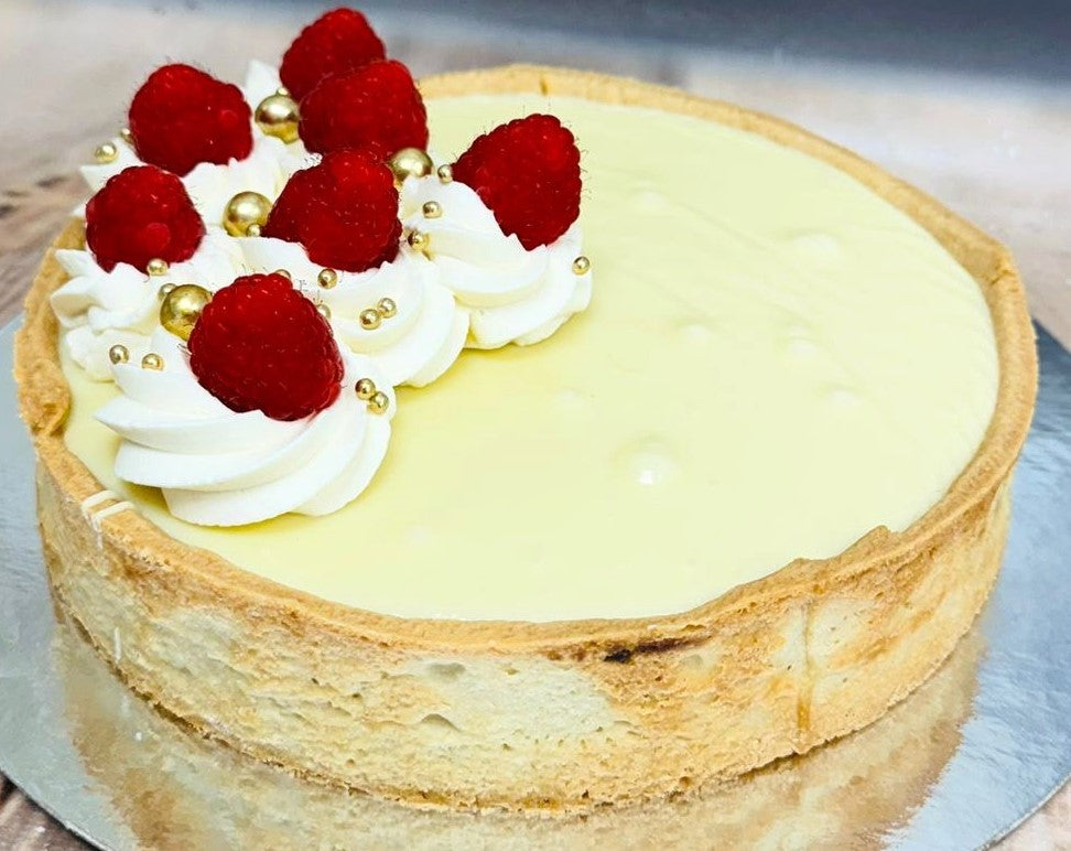Raspberry and white chocolate tart topped with cream and gold pearls